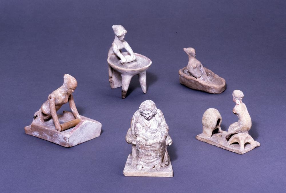 Hellenistic terracotta figure of an enslaved man kneeling at a rotary quern