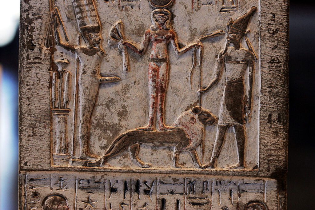 Stela showing Qetesh standing on a lion flanked by Min and Resheph.