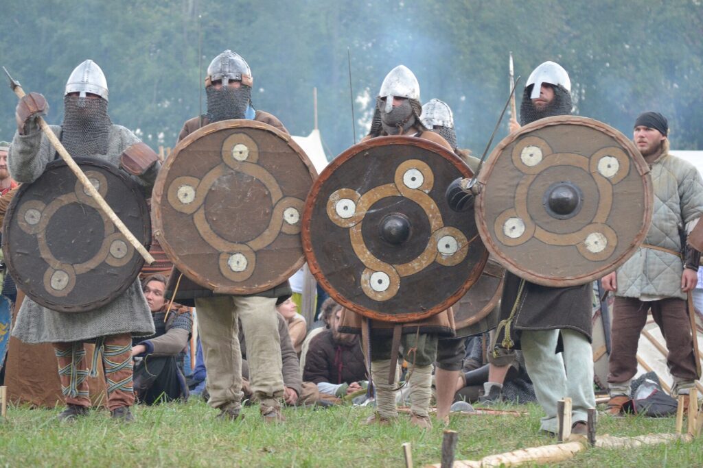 Modern reenactors in formation with Viking shields; rims overlap tightly, showing how a working wall kept cohesion.