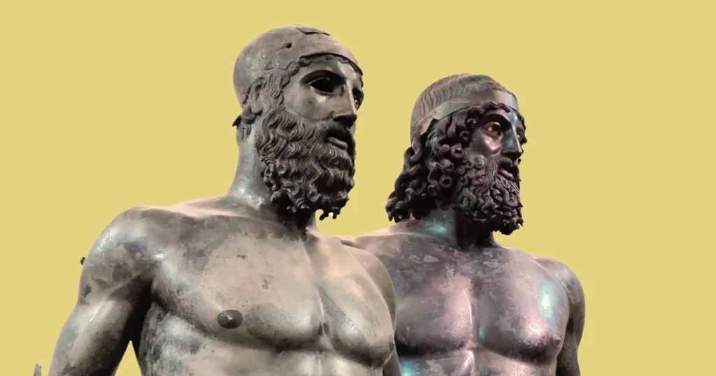 Two Greek bronze warrior statues standing side by side with green patina from underwater preservation