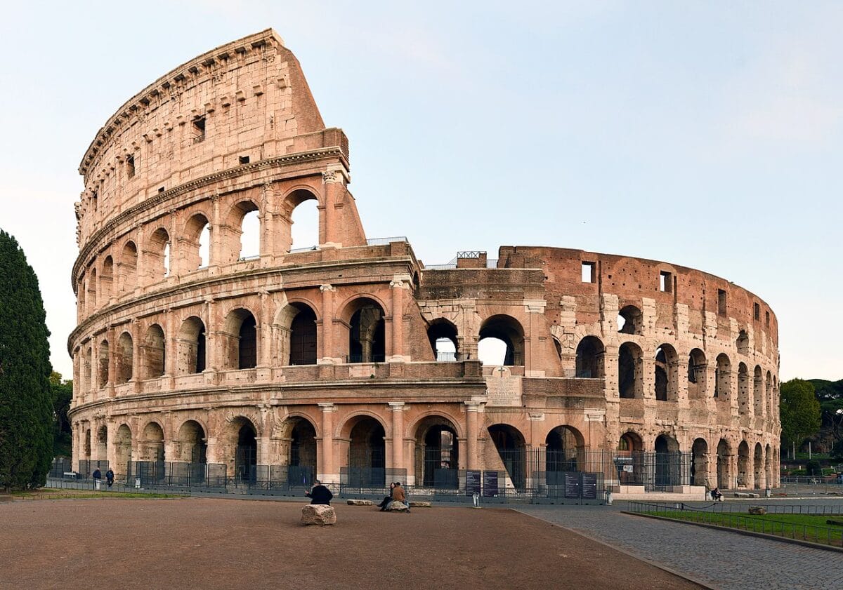 The Colosseum in Rome with its northern outer wall intact, showing three tiers of arched openings, sights to see in Rome